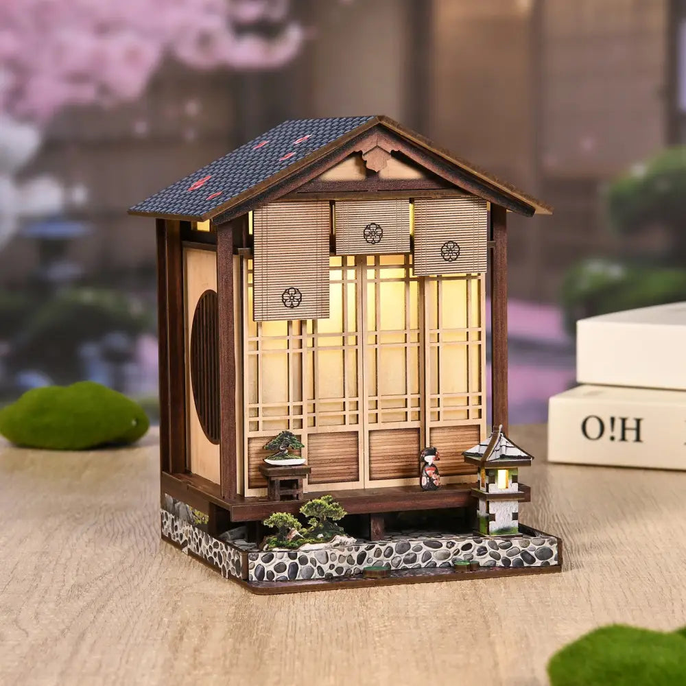 Japanese style wooden miniature house with dark blue tiled roof and led light in moss-lantern harmony garden australia