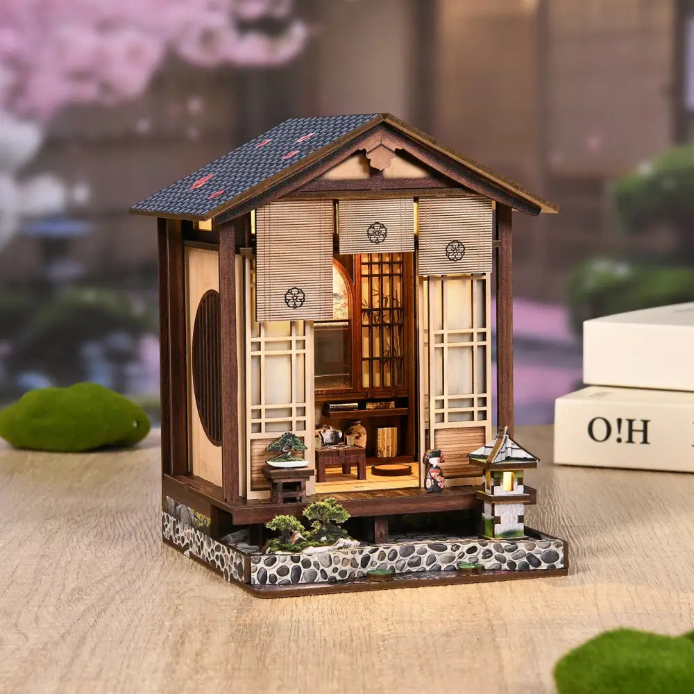 A miniature japanese-style wooden house with dark blue tiled roof and led light in moss-lantern harmony australia