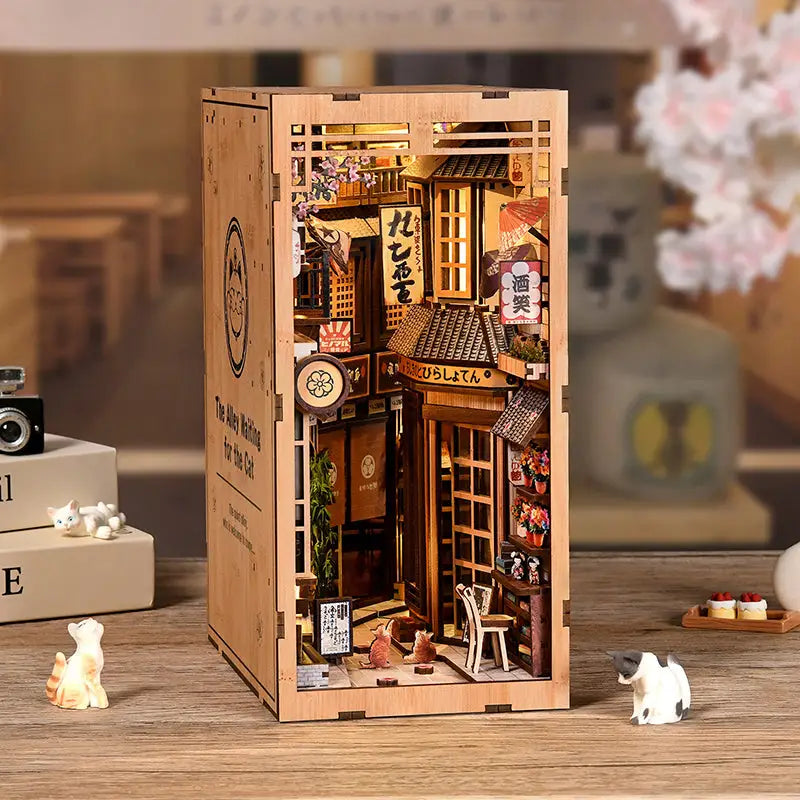 Alley cat cafe book nook diorama with tiny wooden Japanese cats and warm lights