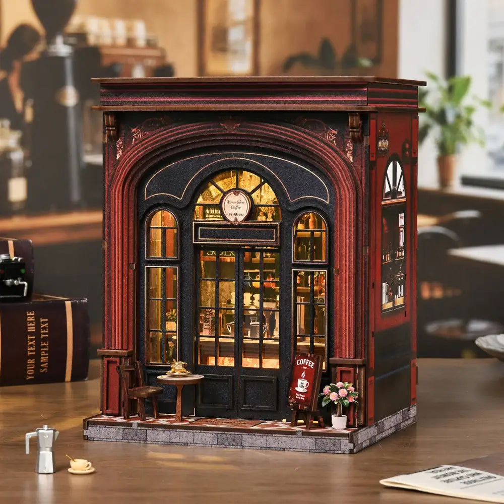 A warmglow coffee diy book nook featuring a detailed miniature coffee shop with dark red and black facade and lit interior